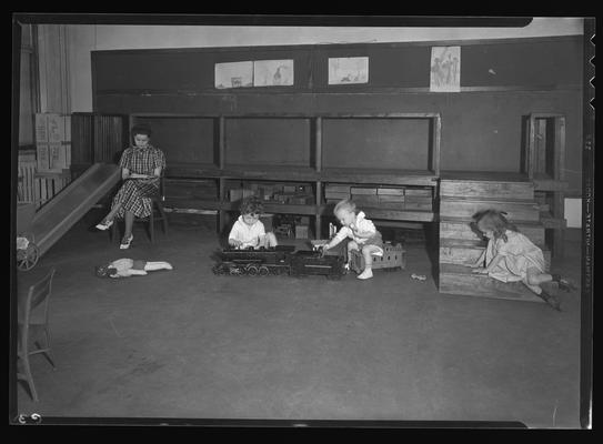 University kindergarten; interior, children playing with train