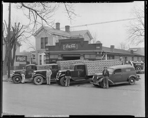 Coca-Cola Bottling trucks in Mt. Sterling; men standing in front of trucks and building