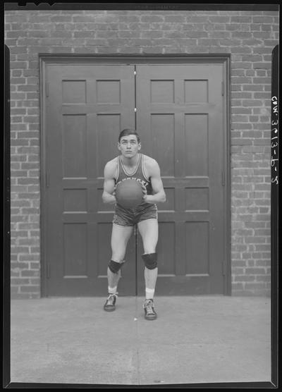 University of Kentucky Athletic Association; unknown basketball player standing in front of closed doors with basketball