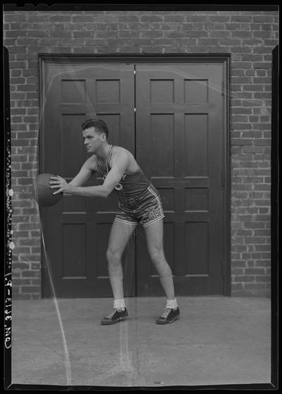 University of Kentucky Athletic Association; Charles Combs (basketball player) standing in front of closed doors with basketball