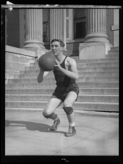 Paris High School ; unknown basketball player in uniform holding a ball, standing on steps of building