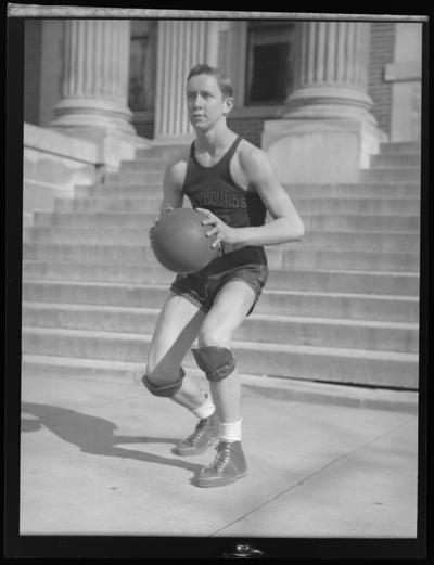 Paris High School ; unknown basketball player in uniform holding a ball, standing on steps of building