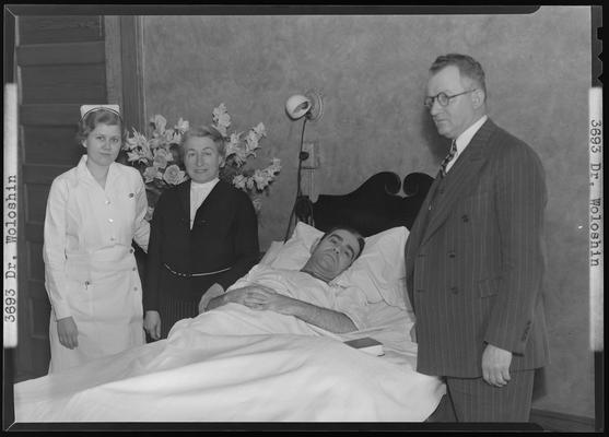 Dr. B. Woloshin and nurse with ill patient who is laying in bed