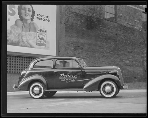 Deluxe Cab Company, 506 West Main; Deluxe Cab car parked in front of tobacco ad on exterior of building