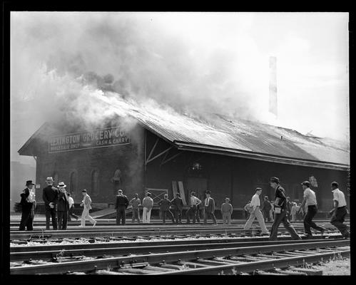 C&O Freight House (Lexington Grocery Company); building on fire, men watching from railroad tracks