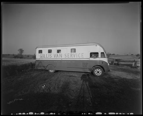 Gillis Van Service; truck #9 parked in field; man in van, shadow of photographer captured in image