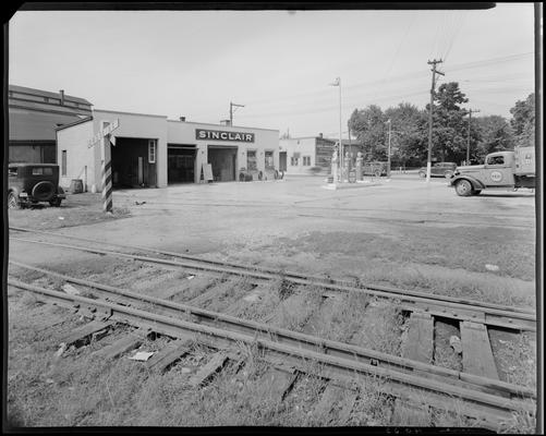 Sinclair Filling Station; exterior; gas station on far side of railroad tracks (service station), Nehi (RC cola) delivery truck in parking lot