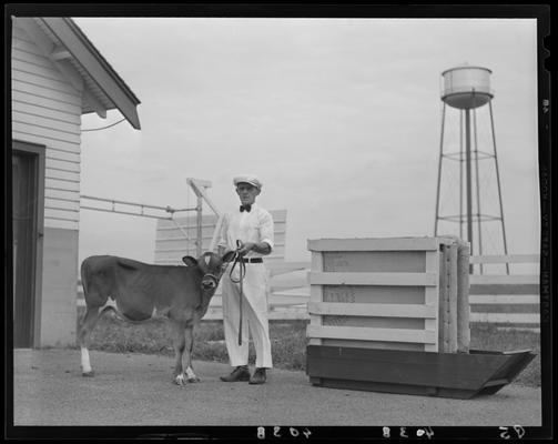 Spindletop Farm; man with bull calf on leash, Tattoo, water tower in distance