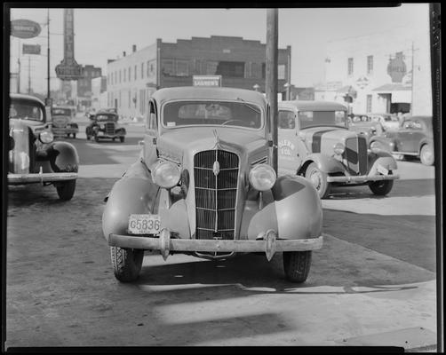 Taylor Bartlett; wrecked car parked in front of Lexington Auto Body Works (413 East Vine), 1938 Clark County Kentucky license plate number 