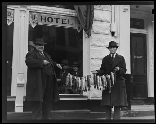Ernest Welch & Ed Wiseman holding stringer of fish in front of the Drake Hotel (321-335 Short); exterior