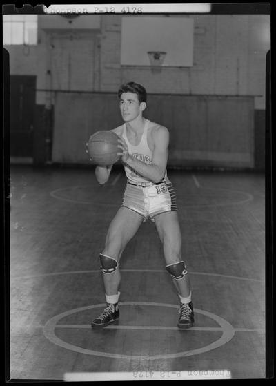 University of Kentucky varsity basketball team; individual team member on basketball court, unidentified number, Thompson poised to throw ball