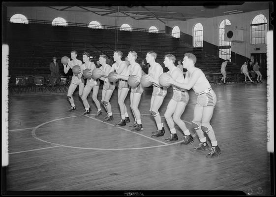 University of Kentucky Varsity basketball team; players standing in file poised to throw balls