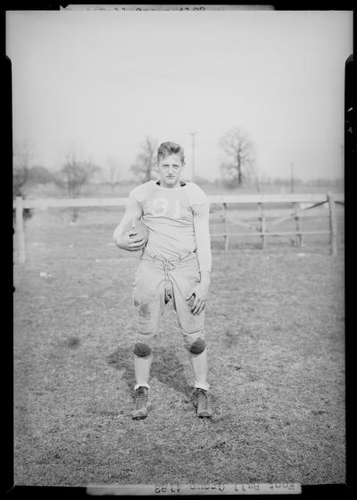 Versailles High School; Football, individual team member portrait, number 31 (no. 31), posing with football under arm on the playing field