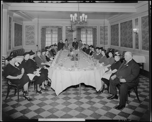 Mr. & Mrs. J.C. Woods & group; sitting at table in dinning room for a banquet