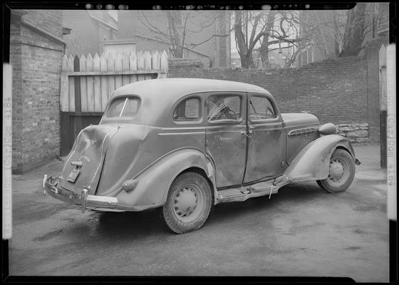 W.W. Williamson; wrecked car parked in front of a garage, damaged passenger's side and rear, rear corner view, Kentucky license plate number N415 (no. N415)car