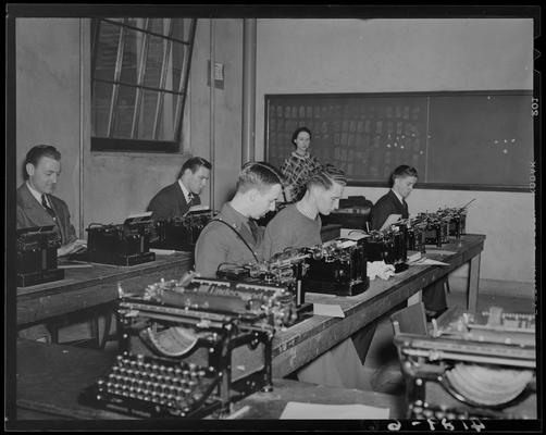 Miscellaneous (1939 Kentuckian) (University of Kentucky); men sitting in front of typewriters, woman instructor standing in front of class