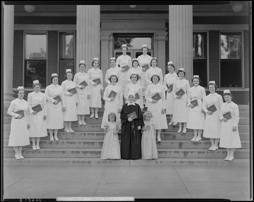 Saint Joseph Hospital, 544 West Second (2nd) Street; nurses' graduation, nurse group portrait, nurses standing on steps of building holding diplomas, two young girls and a nun standing in front of group