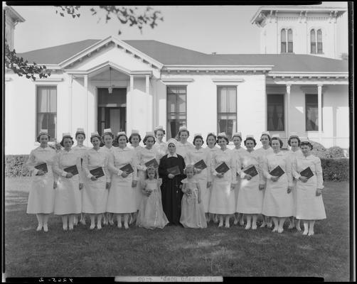 Saint Joseph Hospital, 544 West Second (2nd) Street; nurses' graduation, nurse group portrait, nurses standing outside of building on the lawn, holding diplomas, two young girls and a nun standing in front of group