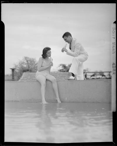 Sour Mash, Kiby Vogt and Joann Young; woman in bathing suit sitting on the edge of a pool, drinking out of a bottle; man standing next to the woman drinking out of a bottle