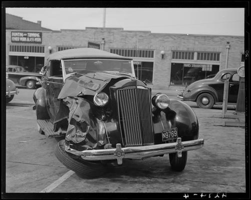 John Crosby; damaged (wrecked) car parked in lot, damaged passenger side and front of vehicle, front view; 1939 Kentucky (KY) license plate Fayette N9769