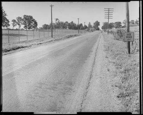 Winganeek Farm & wrecked truck; post accident scene photographs, view looking down the road (U.S. route 25), two men standing on both sides of the road in the distance, telephone poles line both sides of the street (road)