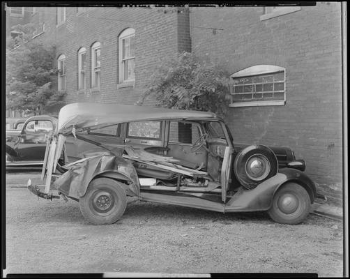 Winganeek Farm & wrecked truck; post accident scene photographs; wrecked (damaged) car parked beside a building, damaged passenger side, view from side