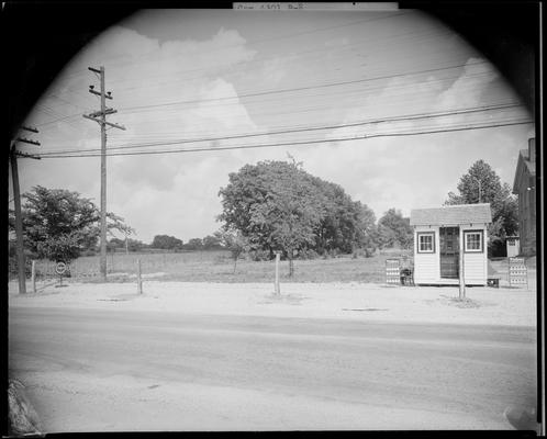 J.S. Morton; gas station (service station); man (attendant) sitting in a chair next to a small gas station building (size of a shed) and three gas pumps, gas station is located along side the roadway, large sign next to pumps reads 