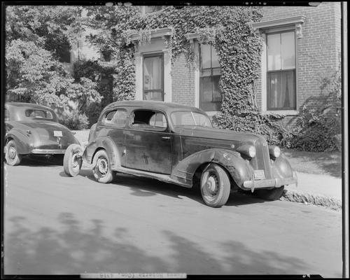 James Roberts; wrecked car; post accident scene photographs, car parked next to building, 1939 Kentucky (KY) license plate number N3257, damaged passenger side