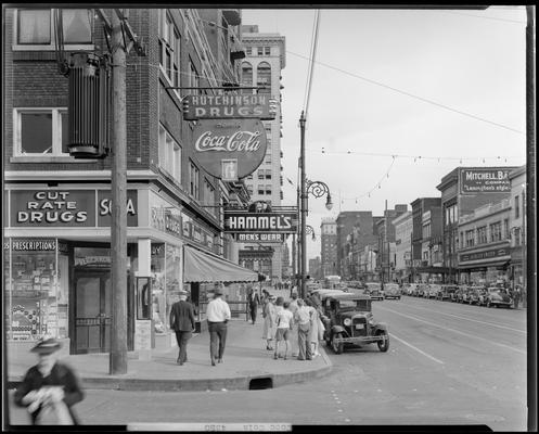 Coca-Cola Company; sign downtown at Hutchinson Drugs (273 East Main); Hammel's Men's Wear (273 West Main); Reed's Millinery (310 West Main); Schulte United Department Store (236-246 West Main); exterior view looking down West Main