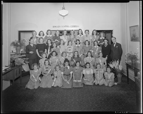 Singer Sewing Machine Company (257 West Short); interior, young girls standing and sitting for a group portrait beneath the 