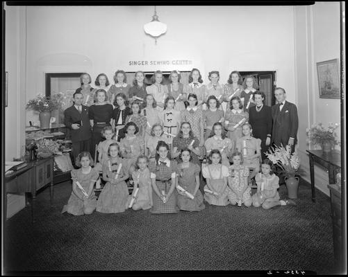 Singer Sewing Machine Company (257 West Short); interior, young girls standing and sitting for a group portrait beneath the 