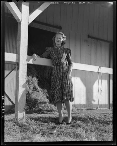 Wildcat Book; girl standing next to a barn, leaning on a wooden railing (modeling)