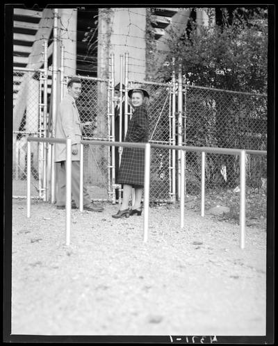 Wildcat Book; a young man and woman standing next to a chain link gate