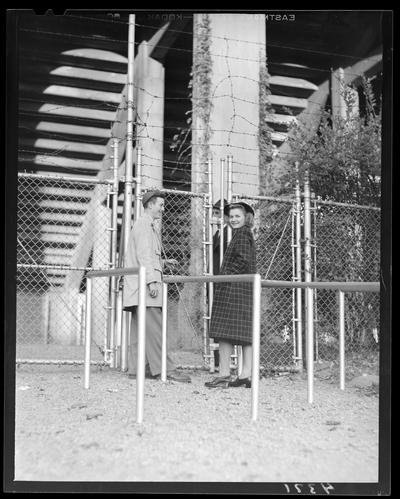 Wildcat Book; a young man and woman standing next to a chain link gate