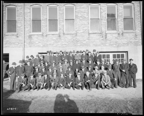 Tobacco Inspection Group; group portrait, large group of men and one woman standing in front of building