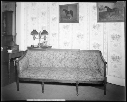 Dixie Antique Shop; sofa, table, lamp, and horse paintings on display behind the sofa