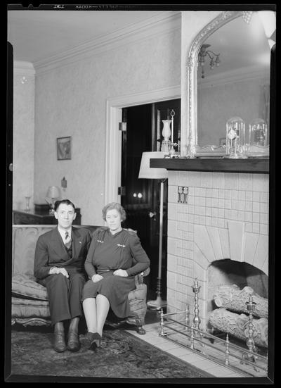 W.B. Griggs; interior of home; man and woman sitting on a sofa (couch, love seat) next to a fireplace