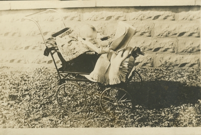 postcard, a baby sitting in a baby carriage holding a newspaper