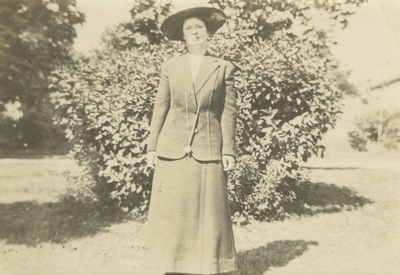 a woman standing outside in front of a bush