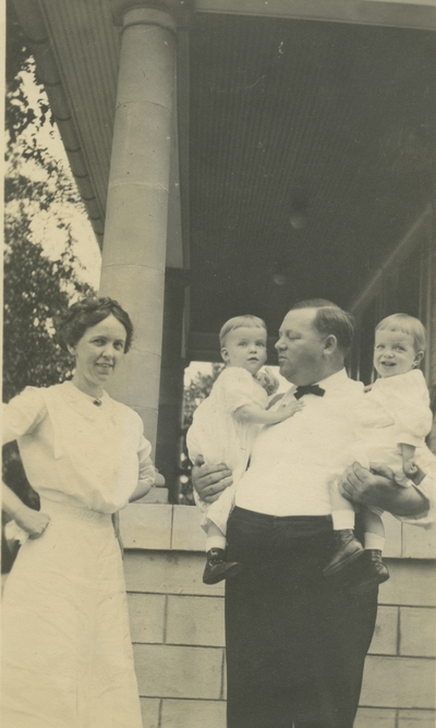 a woman and a man who is holding 2 small children
