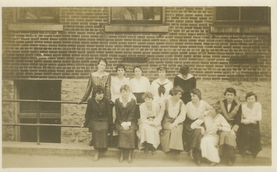 a group of women standing against a building