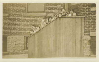 12 women standing behind a small wall so that only their heads are showing