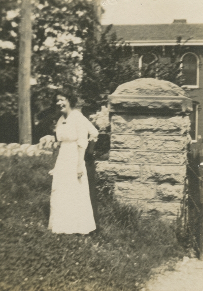a woman standing outside next to a stone wall