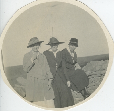 3 women sitting on a stone wall
