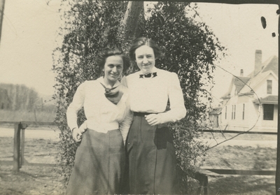 2 women standing next to a tree