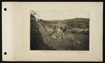 View from above of stooks in field surrounding house and barn, another house and barn in distance, notation                          Hickman Valley Jessamine County Kentucky 1907