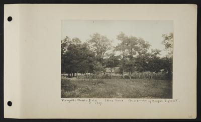 Dilapidated wooden building with stone fence running in front, possibly crops on right side of building, another wooden fence running off in left, notation                          Perryville Battlefield, 1907, stone fence, breastworks of Memphis Regiment