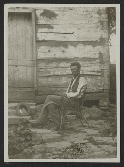 Man sitting in front of log house