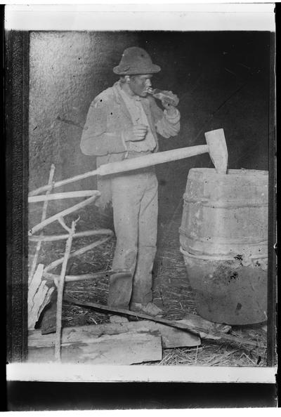 Man standing at barrel, glass negative