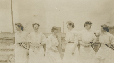 6 unidentified women standing by a fence